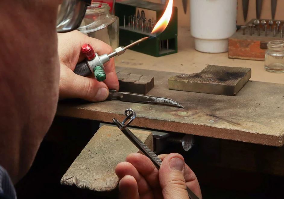 Eric Kojadelian at the jeweller's bench, torch in hand, working on a ring